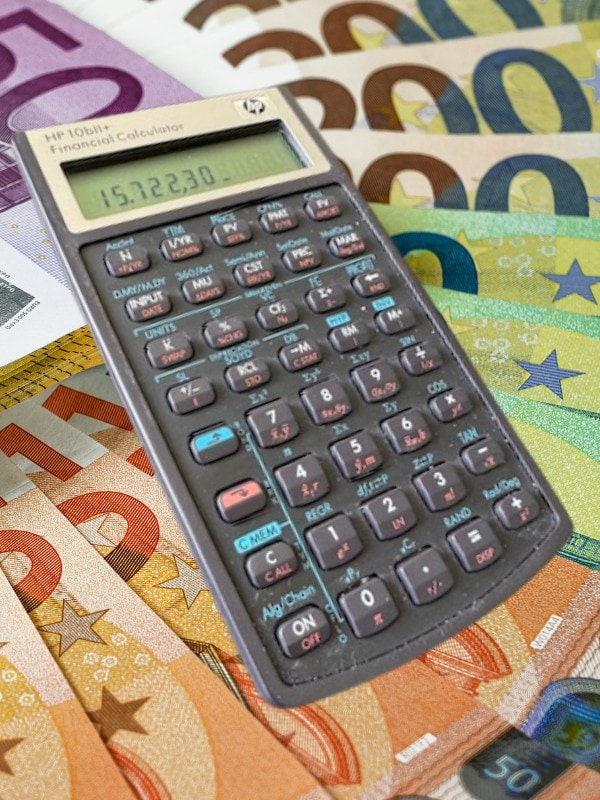 Taschenrechner auf Euro-Geldscheinen als Symbol für Kosten und Wirtschaftlichkeit des Status-Check PREMIUM